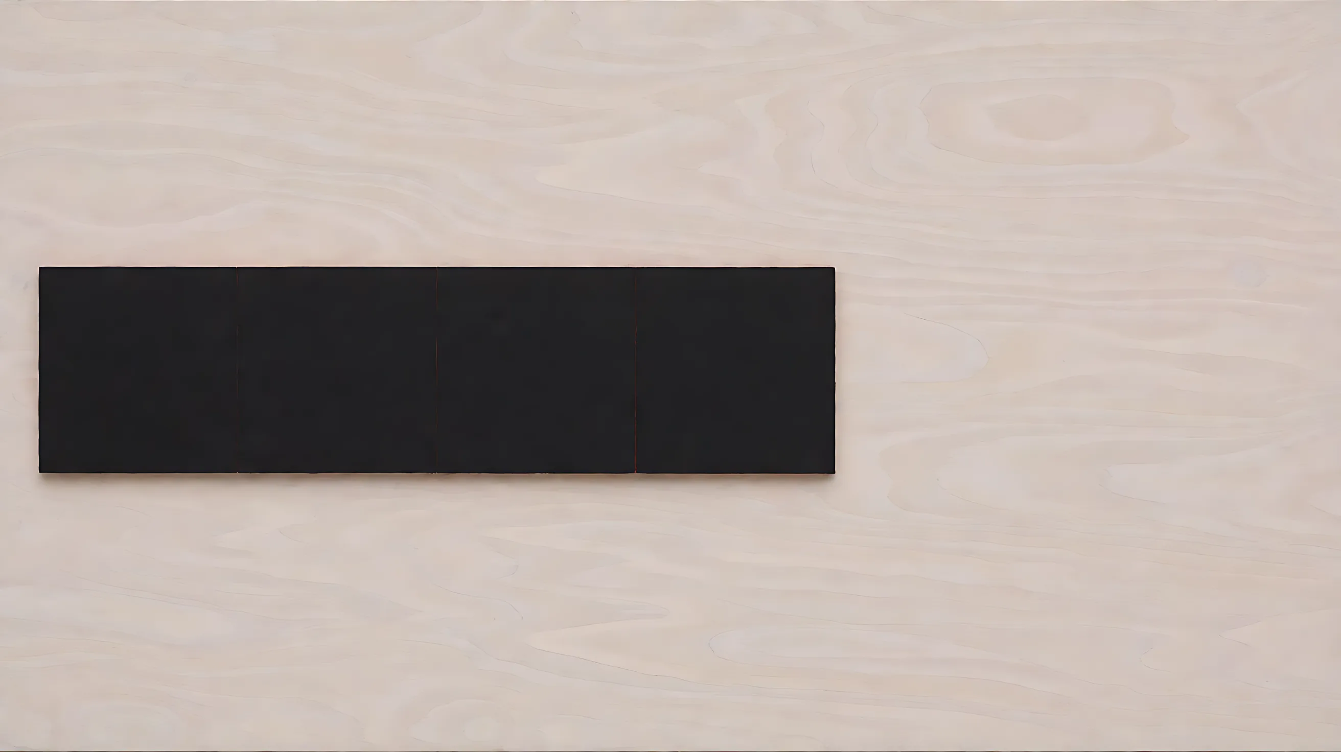 Four black squares joined into one bar on pale wood, with thin red seams and empty wood to the right.