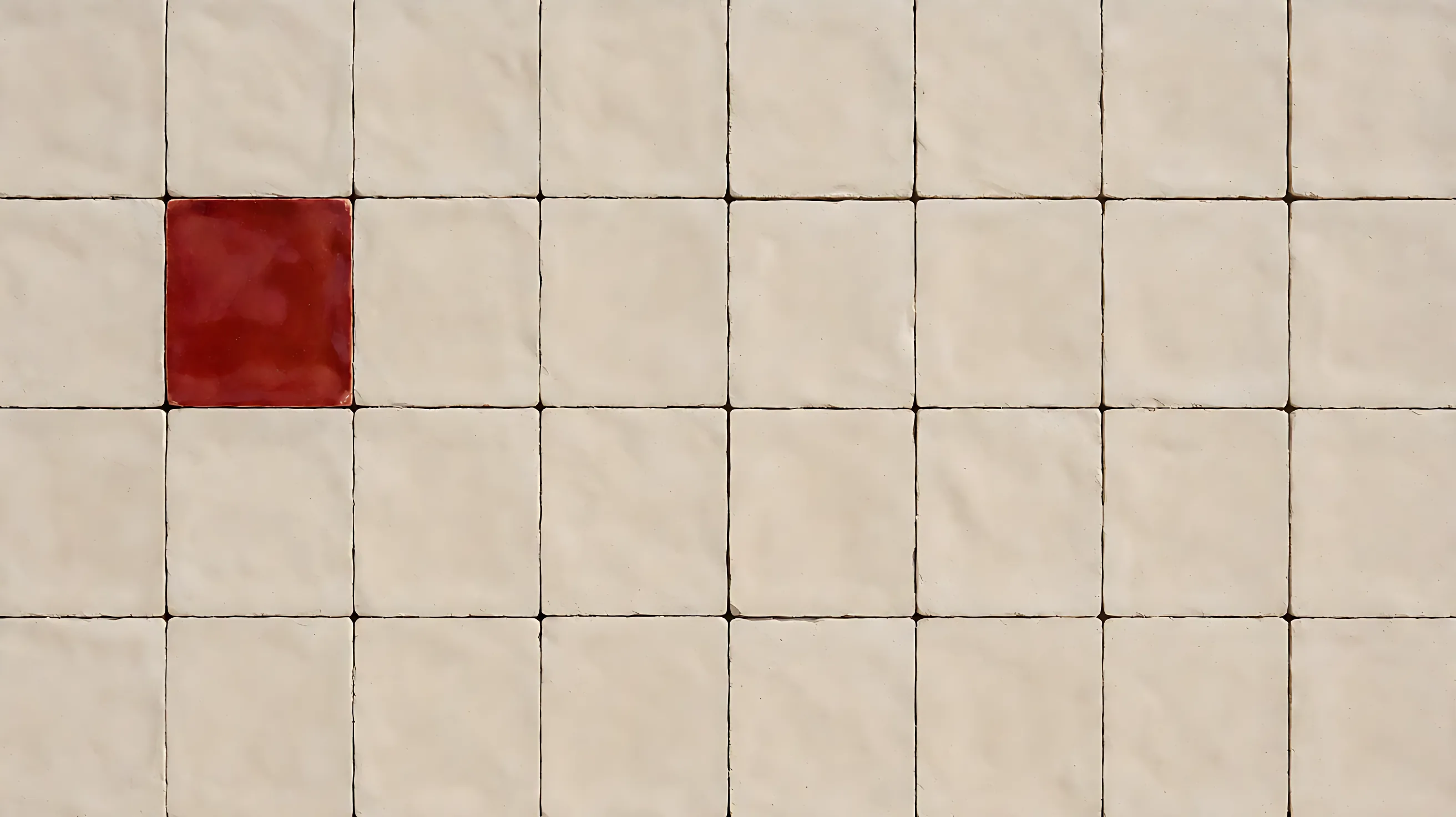 A full field of plain tiles, with a single red glazed tile on the left.